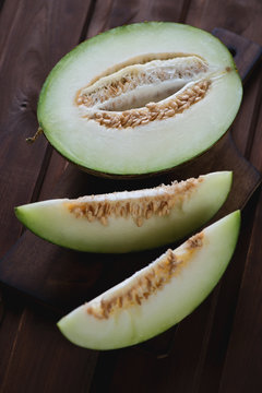 Sliced cantaloupe melon over dark rustic wooden surface, closeup