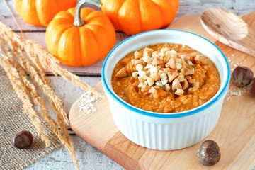 Bowl of autumn pumpkin oatmeal with walnuts, chocolate and peanut butter chips, table scene