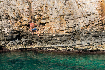 Young athletic man climbing sea cliffs without rope or harness in Croatia