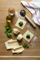Homemade raw Italian tortellini and basil leaves on dark vintage