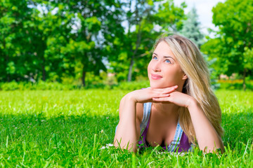 dreamy girl resting on the green grass in the park