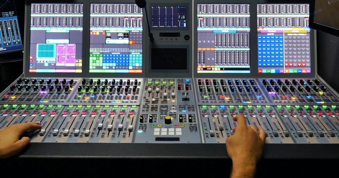 A mans hands pulling the knobs of an audio mixer up and down...