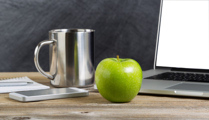 Green apple on an old wooden classroom desktop with technology
