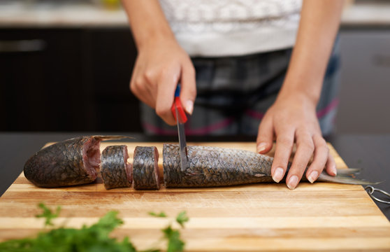girl cuts fish to prepare dinner