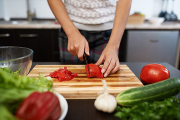 girl chops tomato on salad