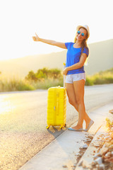 Attractive young woman with a yellow suitcase is traveling on th
