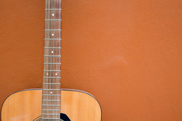 Obraz premium Acoustic guitar leaning on wall background