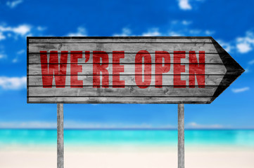 Red We're open wooden sign with on a beach background