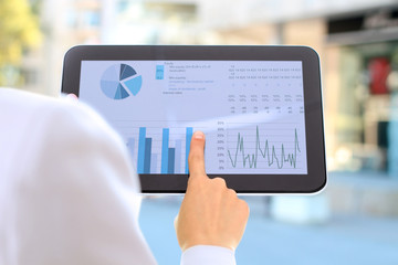 The young businesswoman showing graphs by finger at the digital