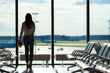 Young woman near window in an airport lounge waiting for flight