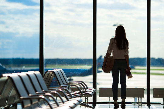 Young woman near window in an airport lounge waiting for flight