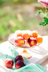 Ripe peaches in in a glass bowl for fruits on the table with marshmallow