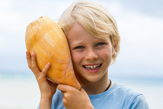 Cute, Smiling Child Holding Baler Shell To Ear Listening