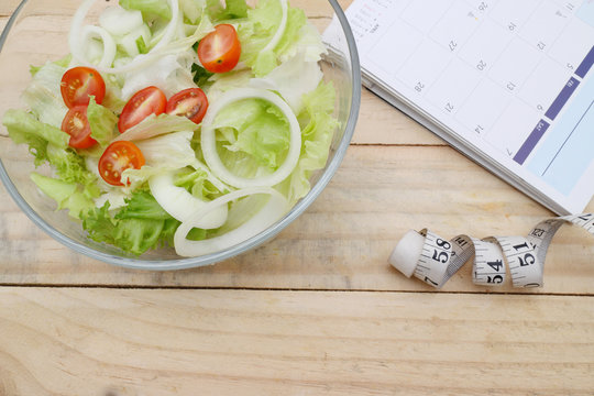 healthy eating, dieting, slimming and weigh loss concept - close up of salad, measuring tape