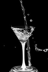 Cocktail glass with splashes isolated on a black background.