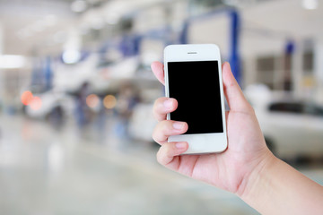 hand hold smartphone with car repair service center background