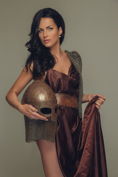 Portrait of brunette woman with encient helmet in her arm.