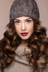 Beautiful girl with gentle makeup, curls in brown knit hat. Warm