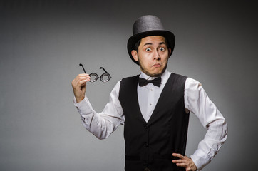 Young man in classical black vest and hat against gray