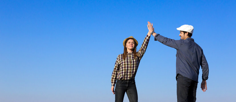 Man and Woman Clapping Hands Each Other Two People Expressing Happiness and Enjoying Success Touching Hands Arms Raised Casual Jeans Style Clothing Blue Sky Background