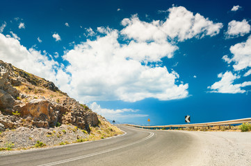 Road in the mountains and dark blue sky with white clouds