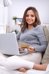 Beautiful smiling woman with laptop and a credit card