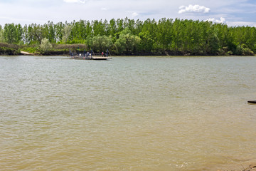 People are moving manual ferry boat across the river.