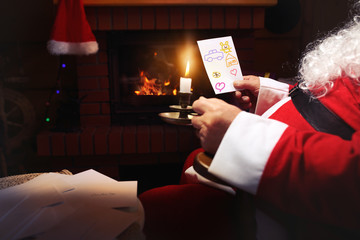 Santa Claus reads letters written by children around the fireplace
