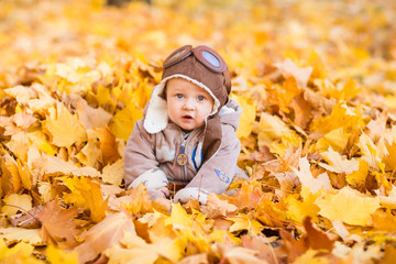 Cute baby in autumn leaves.