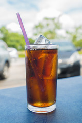 glass of soft drink with ice cubes on table