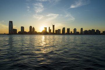 Sunset silhouette city skyline of Jersey City and Hoboken New Jersey from across the waters of the Hudson River in New York City
