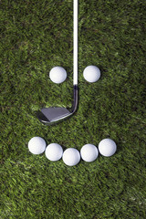 Golf club and balls on green grass