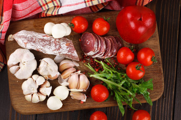 Salami with cherry tomatoes, pepper, garlic and ruccola on a cut