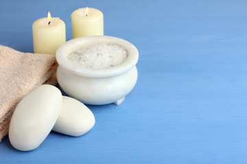 Obraz na płótnie Canvas candles and soap with sea salt and towel on blue background