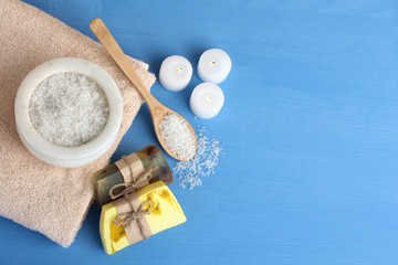 candles and soap with sea salt and towel and wooden spoon on blue background