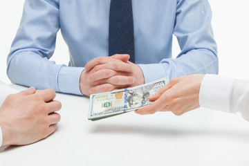 Female hand shoving money under business partner's hand