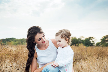 mother and daughter playing on autumn field together, loving family having fun outdoors
