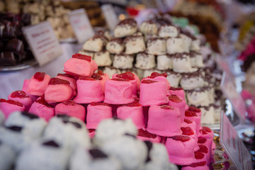 Lots of different kinds of marzipan are arranged in stacks. There are flavors such as chocolate, vanilla, strawberry, raisins, coconut and more.
