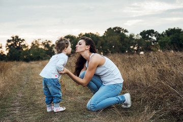 mother and daughter playing on autumn field together, loving family having fun outdoors