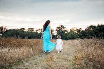 mother and daughter playing on autumn field together, loving family having fun outdoors