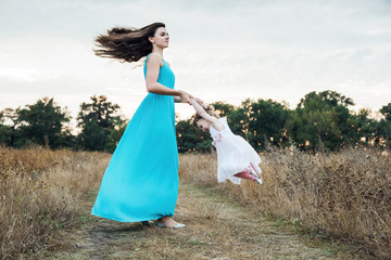 Fototapeta premium mother and daughter playing on autumn field together, loving family having fun outdoors