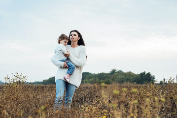 mother and daughter playing on autumn field together, loving family having fun outdoors