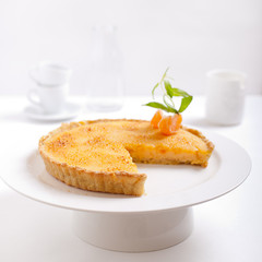Tangerine creme brulee tart on a white background