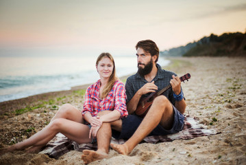 Obraz premium caucasian couple on seaside playing ukulele 