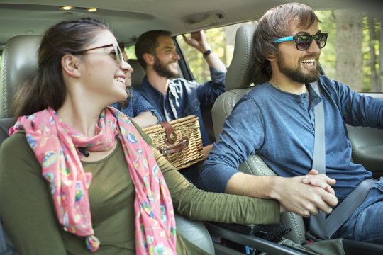 A group of people inside a car, on a road trip. 