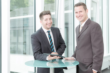 Zwei Geschäftsleute bei einer Besprechung am Stehtisch