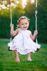 Adorable baby girl enjoying a swing ride on a playground in a park