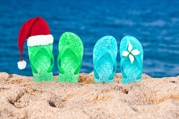 Christmas hat on flip flops in the sand of a beach