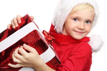 Świąteczne prezenty, radość dziecka. Szczęśliwe dziecko w czapce św. Mikołaja z zapakowanym prezentem