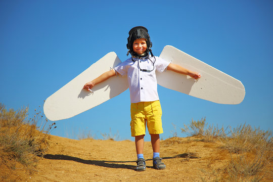 kid with wings and flying helmet plays in the plane